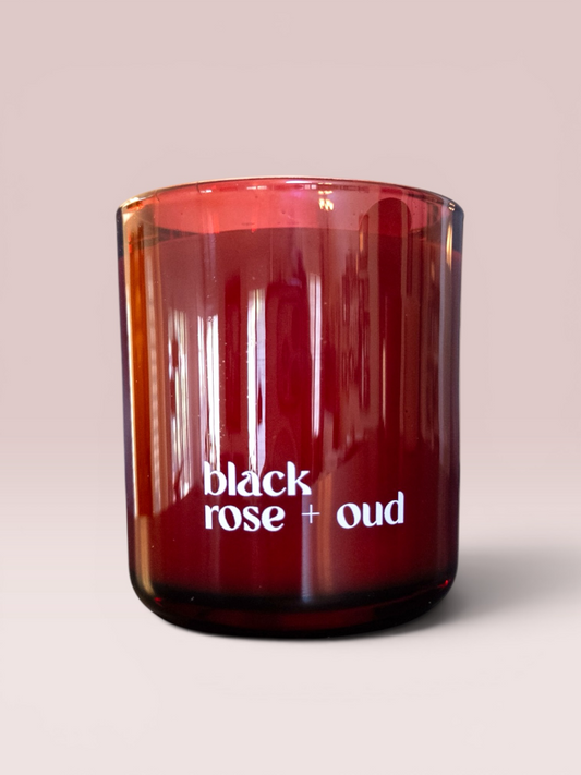 Black Rose + Oud 9 oz double-wick candle in a deep red glass vessel.
