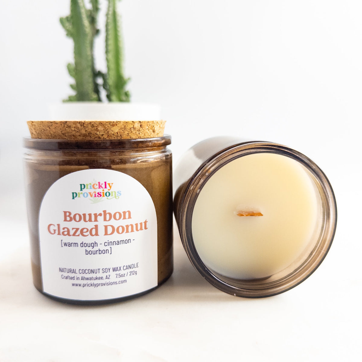 Candle in a glass jar with a cork lid and visible label on a white background