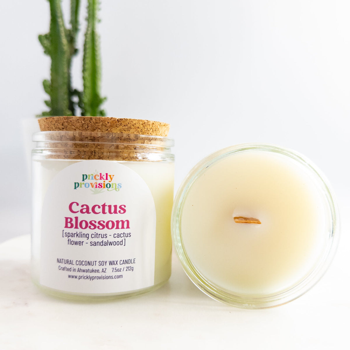 Candle labeled 'Cactus Blossom' by Prickly Provisions with a cactus plant in the background.