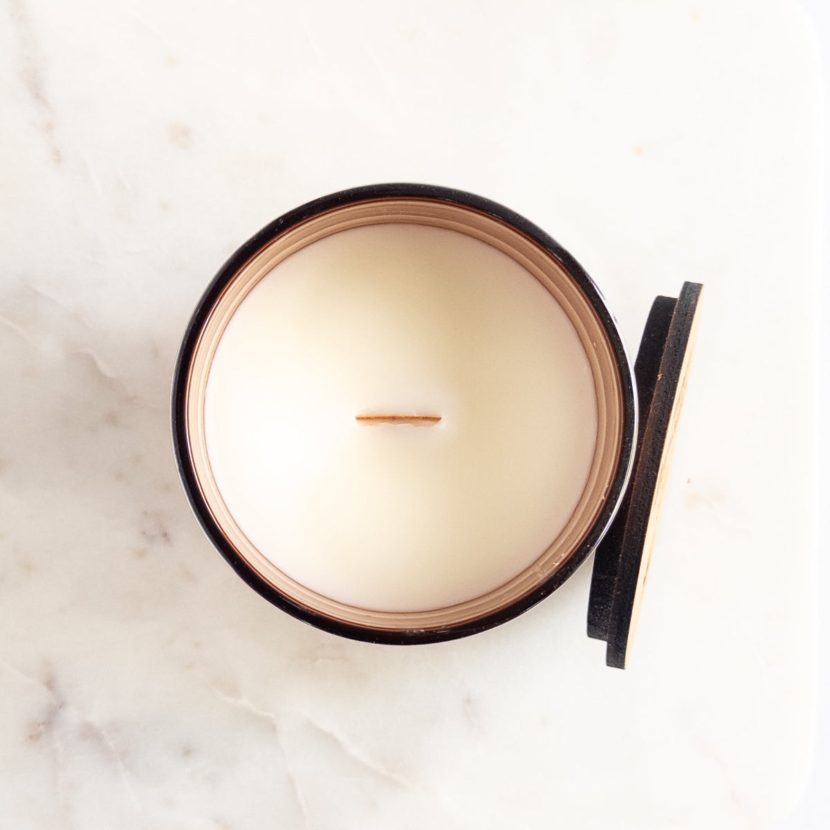 Candle in a copper container on a marble surface