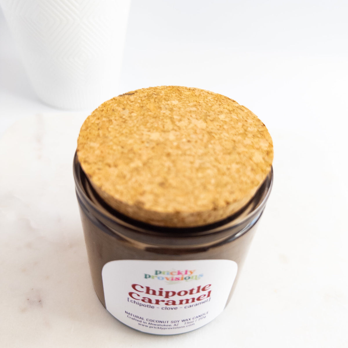Jar of 'Chipotle Caramel' candle with cork lid on a white background