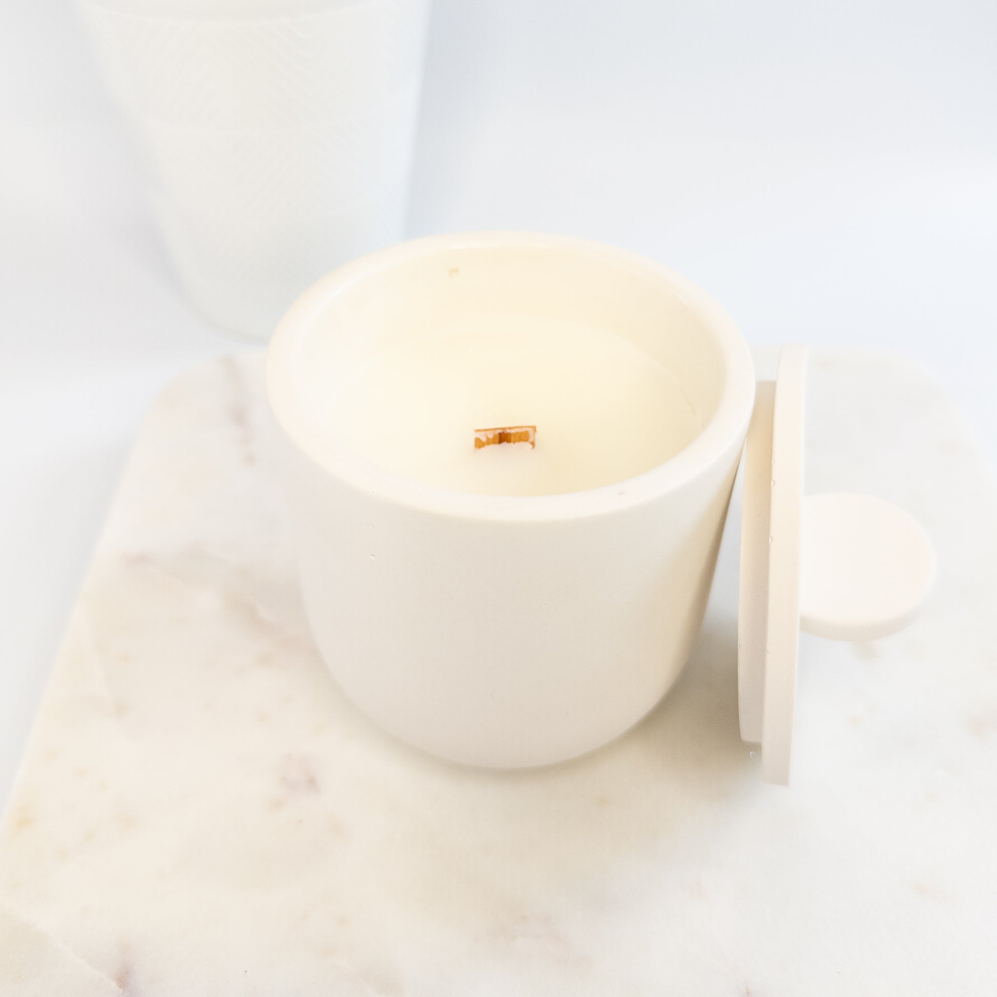 White candle in a cement holder on a light background