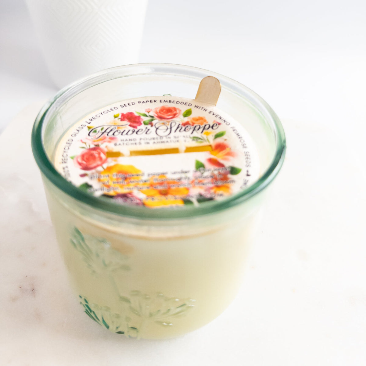 Candle in a glass jar with a floral label on a white background