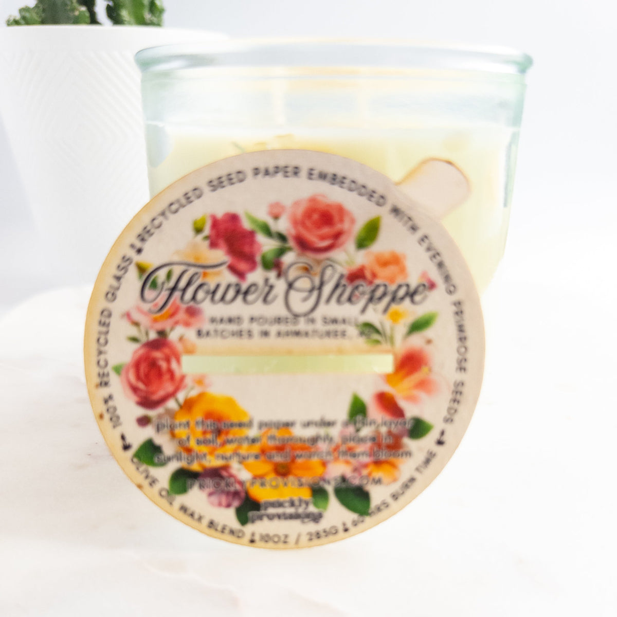 Candle with a decorative label featuring floral designs and text.
