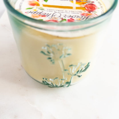 Jar of cream candle with decorative label on a white background