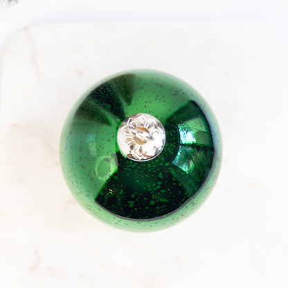 Green Christmas ornament candle on a white background