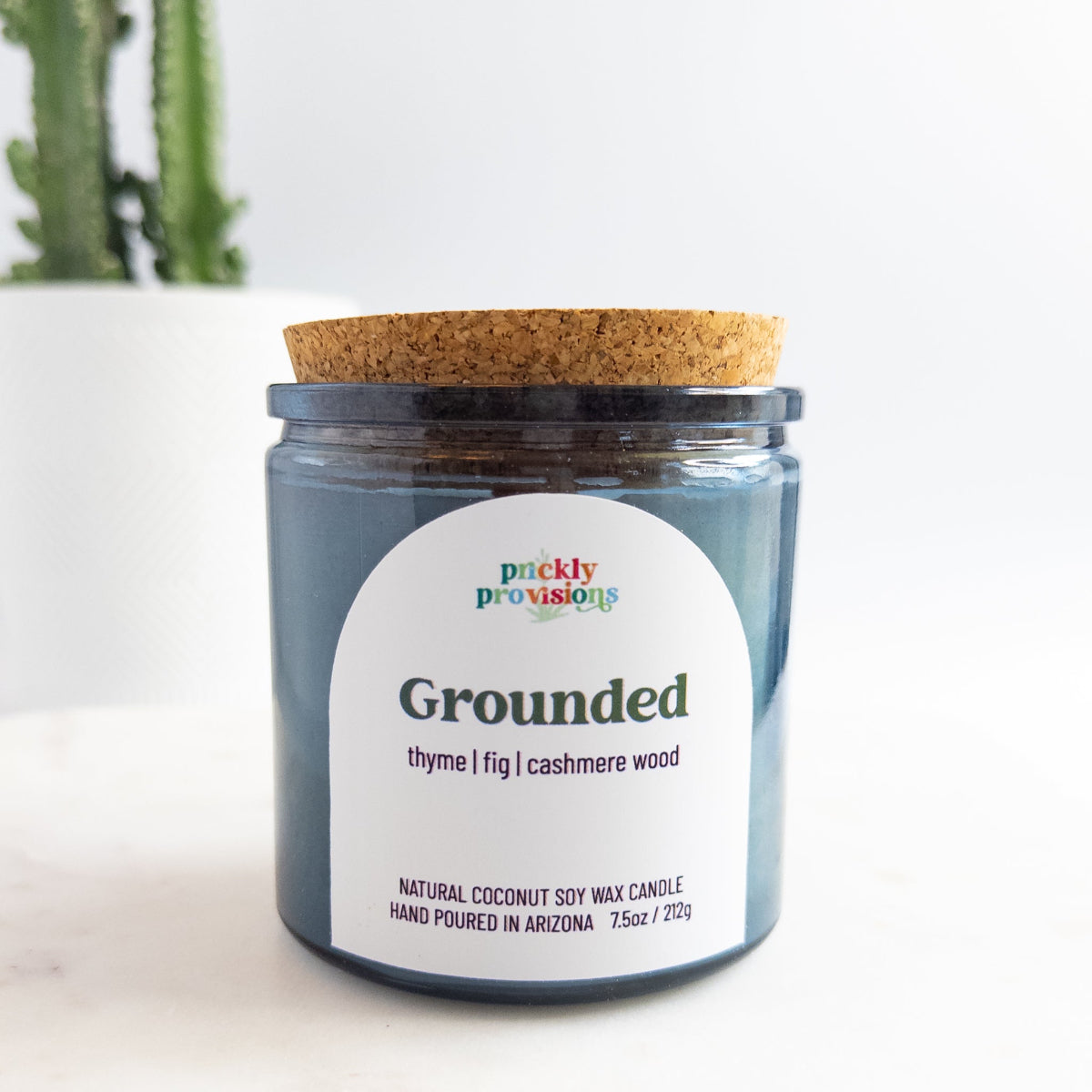 Candle jar labeled 'Grounded' by Prickly Provisions on a white background
