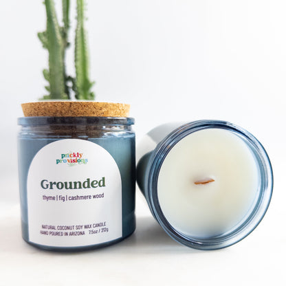Candle jar labeled 'Grounded' by Prickly Provisions with a cactus in the background.