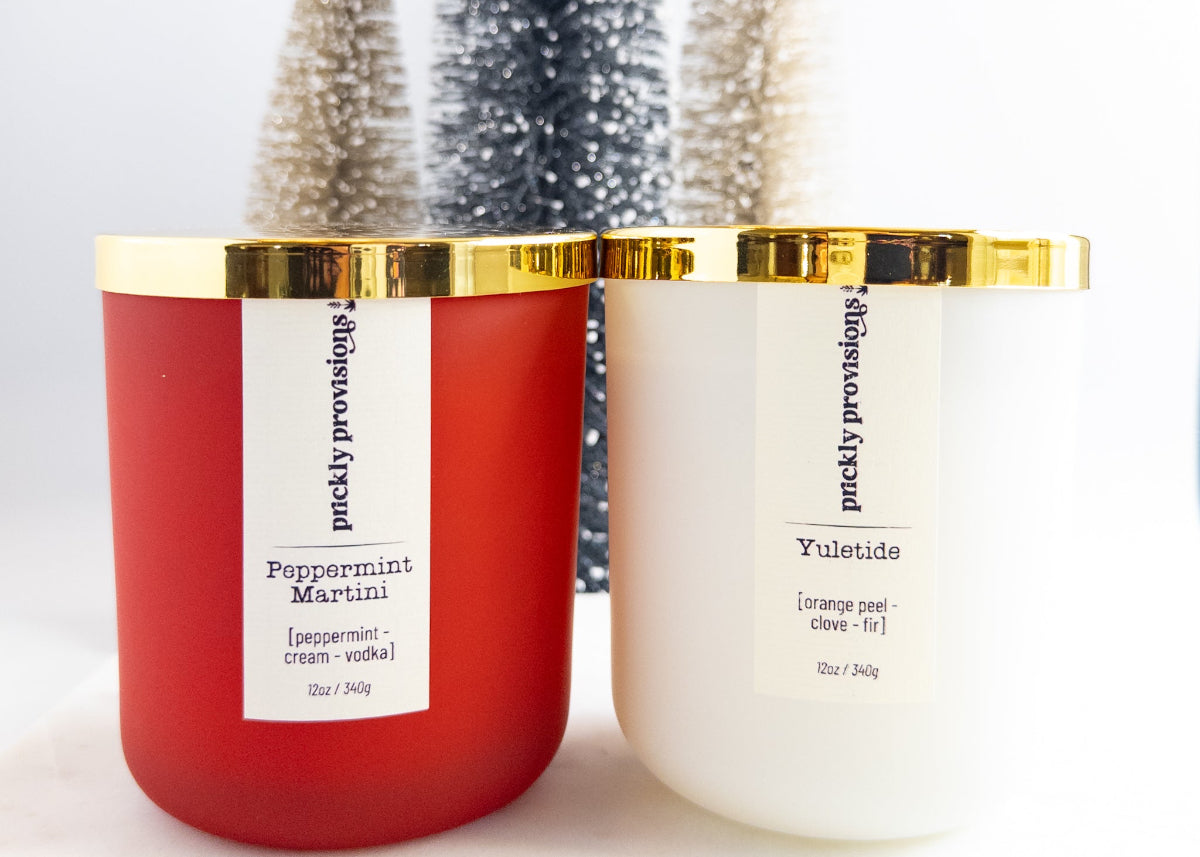 Two candles with gold lids, one red and one white, on a light background.