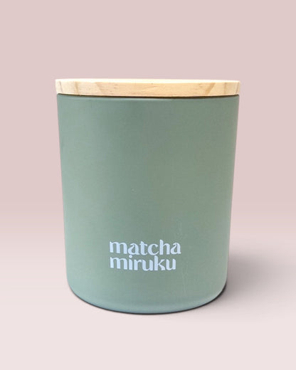 Matcha Miruku 9 oz double-wick candle in matte sage-green glass with wooden lid
