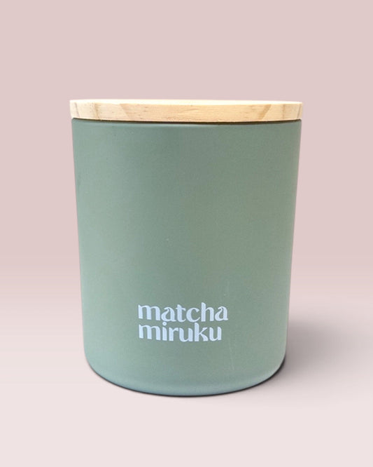 Matcha Miruku 9 oz double-wick candle in matte sage-green glass with wooden lid
