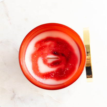 Red candle with a white swirl on a white marble surface