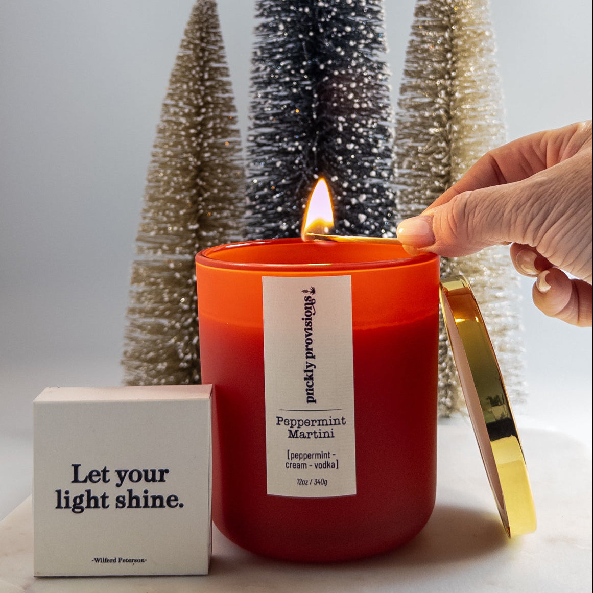 Red candle being lit with decorative trees in the background