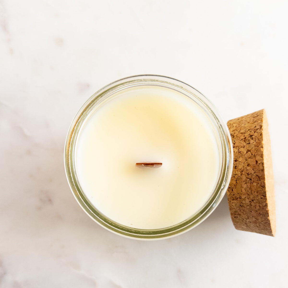 Candle in a glass jar with a cork lid on a light background