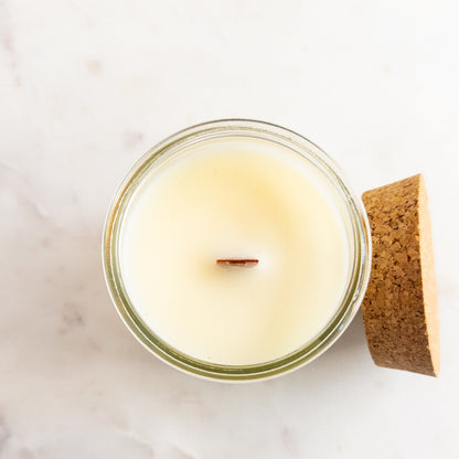 Candle in a glass jar with a cork lid on a light background