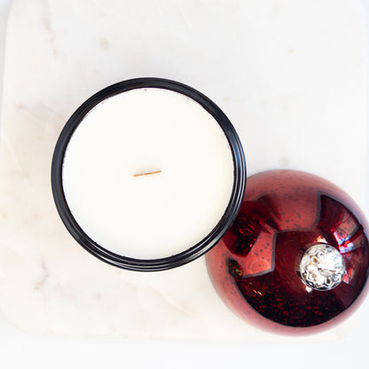 Christmas ornament candle with a decorative red cover featuring a wooden wick on a white background