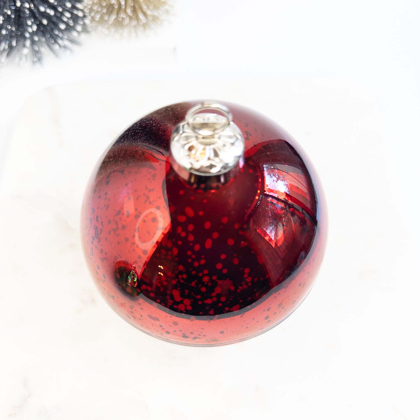 Red glass Christmas ornament candle with a silver hanging loop on a white background
