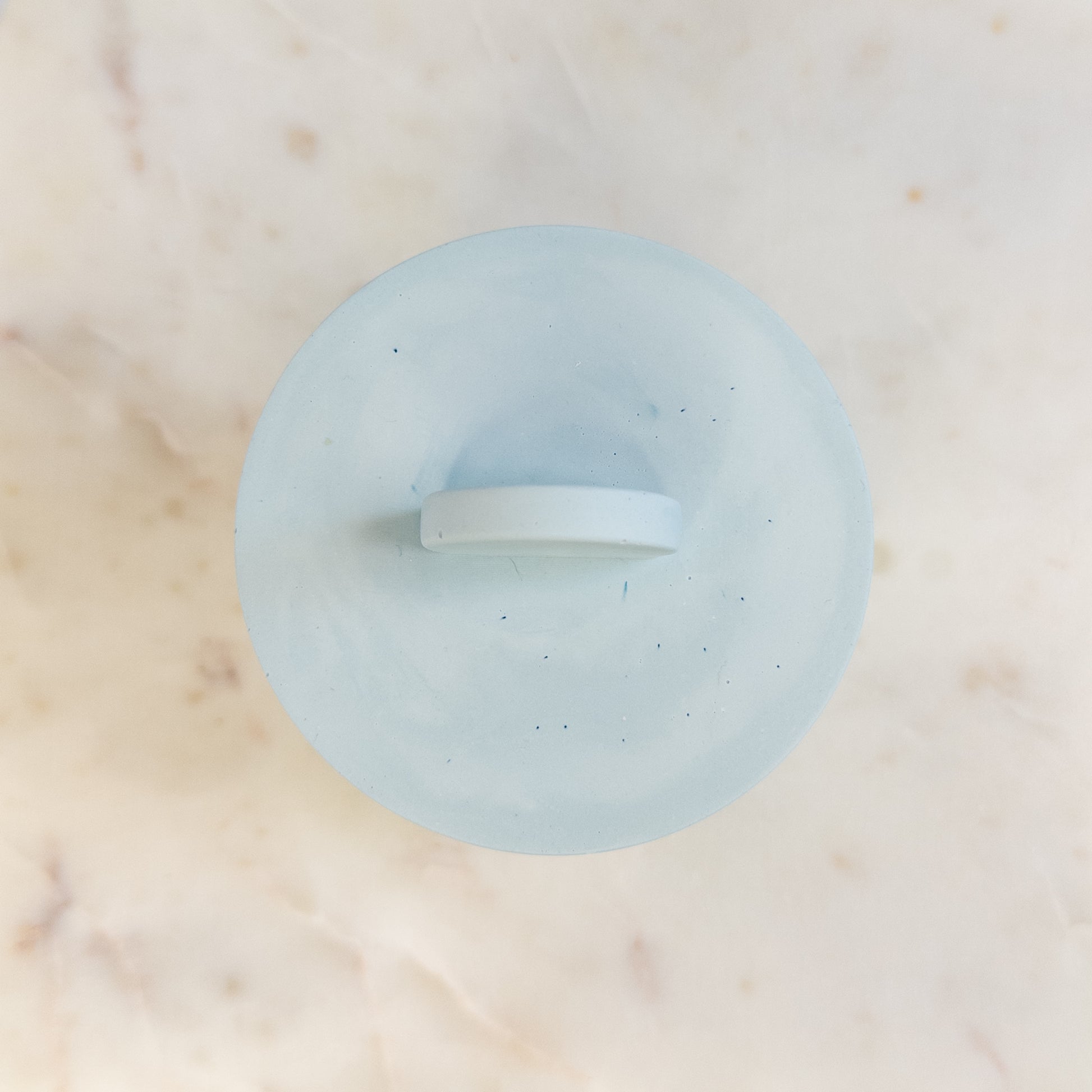 Light blue cement candle with lid on a marble surface