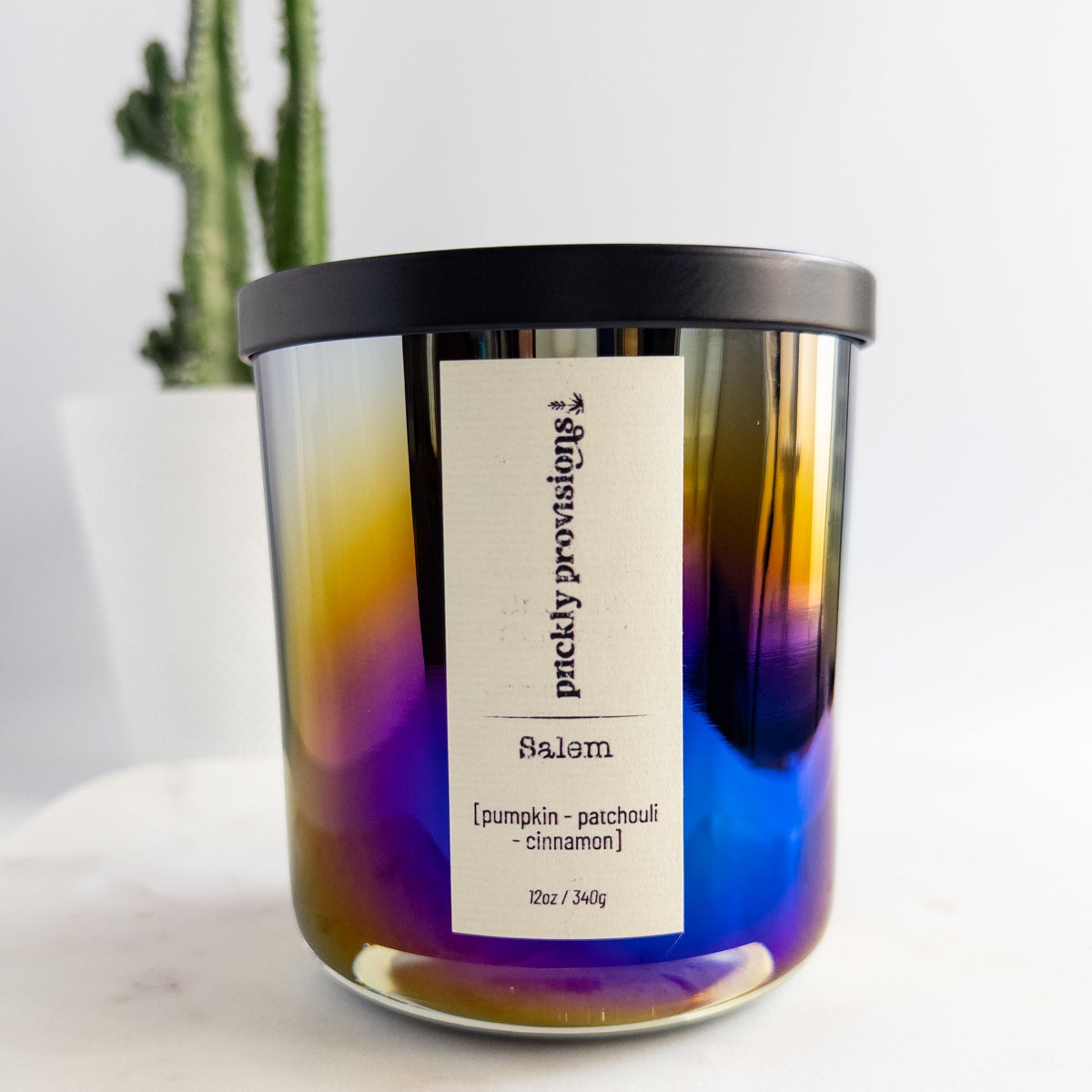Candle with a label on a white surface, featuring a gradient of purple and blue colors.
