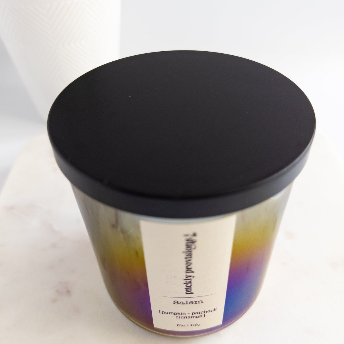 Candle with a black lid on a white marble surface