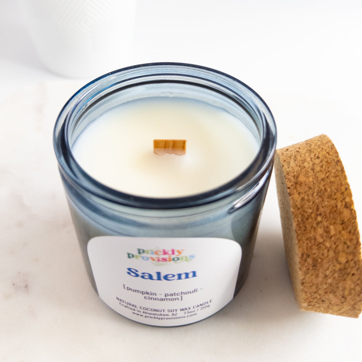 Candle in a glass jar with a cork lid on a white background