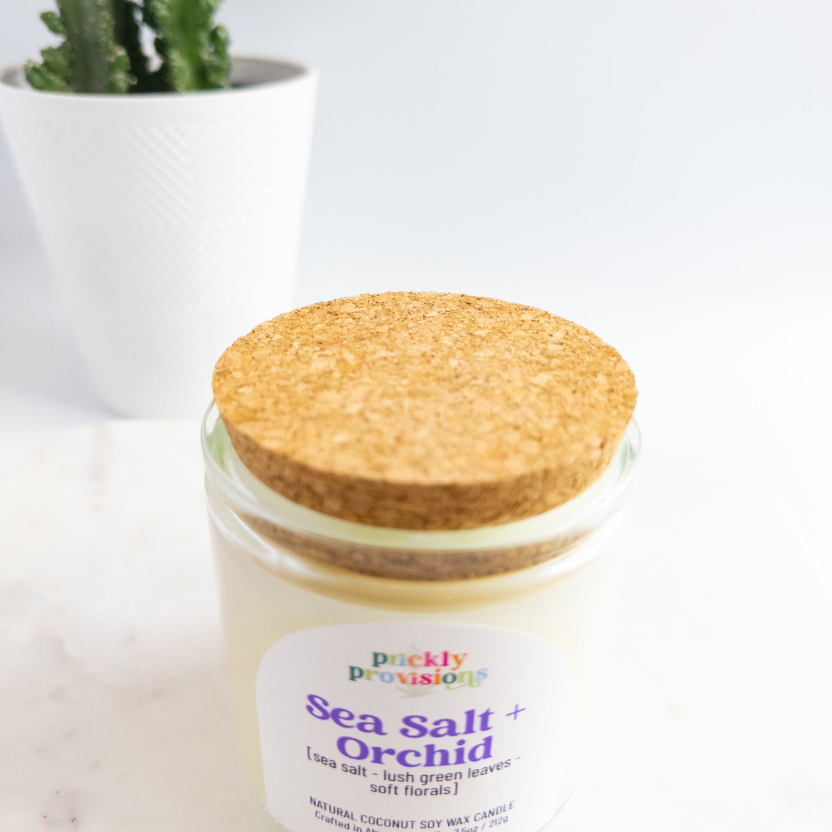 Candle jar with cork lid labeled 'Sea Salt Orchid' from ' prickly provisions' on a white background.