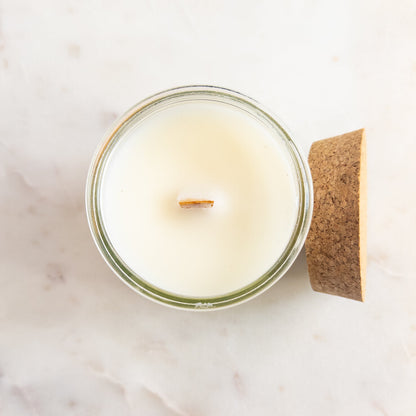 Candle in a glass jar with a wooden lid on a marble surface