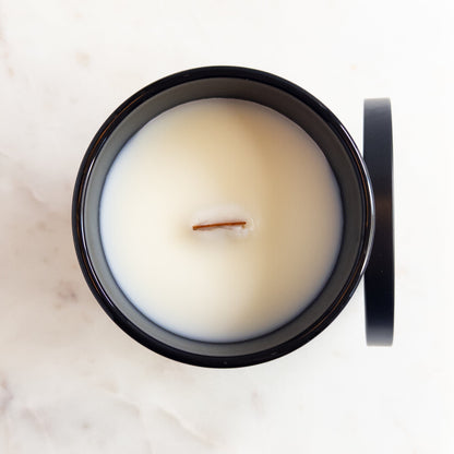 White candle in a black container on a marble surface