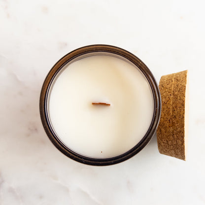 Candle in a glass jar with a wooden lid on a light background