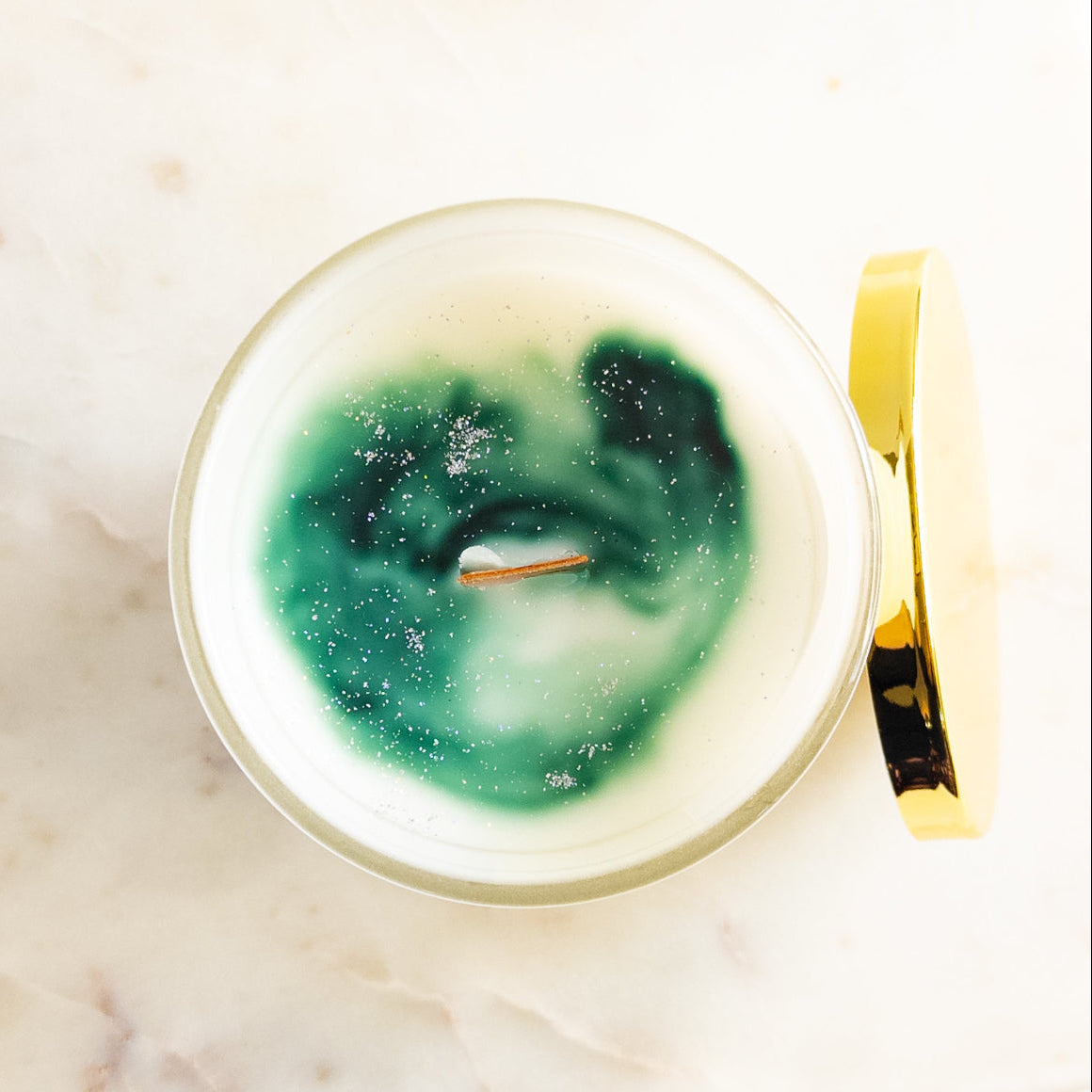 Decorative candle with green and white design on a marble surface