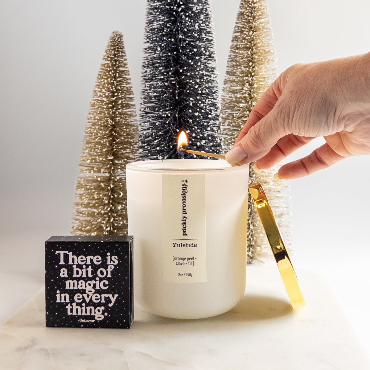 Candle being lit with decorative trees and a quote block in the background